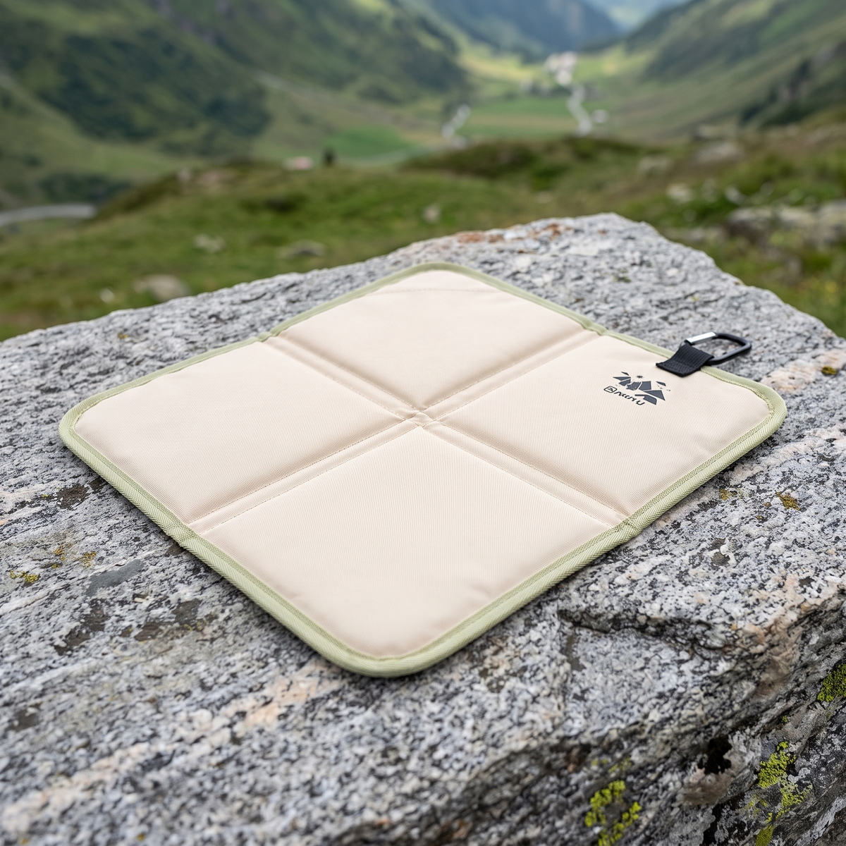 Bergkraft Sitzkissen in Cremeweiss, aufgeklappt auf einem Felsen in den Bergen