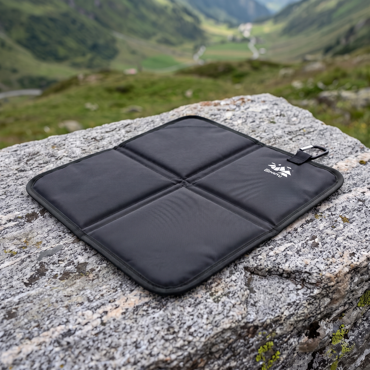 Bergkraft Sitzkissen in Schwarz, aufgeklappt auf einem Felsen in den Bergen