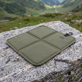 Bergkraft Sitzkissen in Militaergruen, aufgeklappt auf einem Felsen in den Bergen