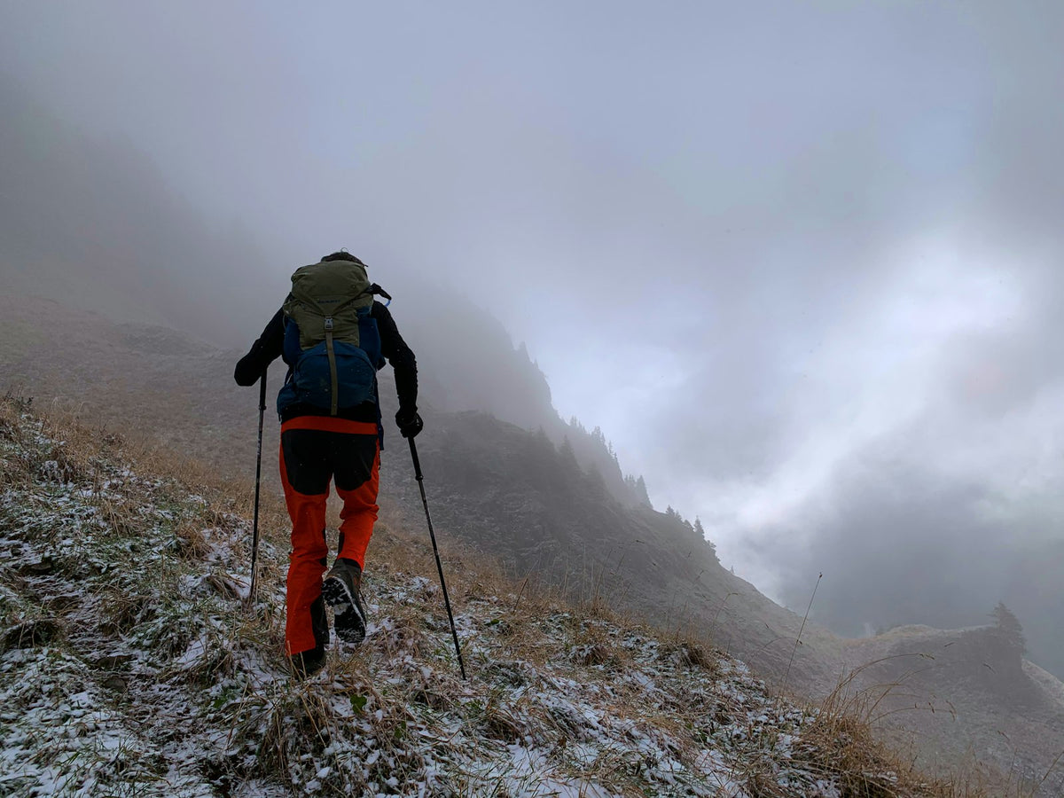 Wanderer mit Rucksack auf steinigem Wanderweg in den Bergen